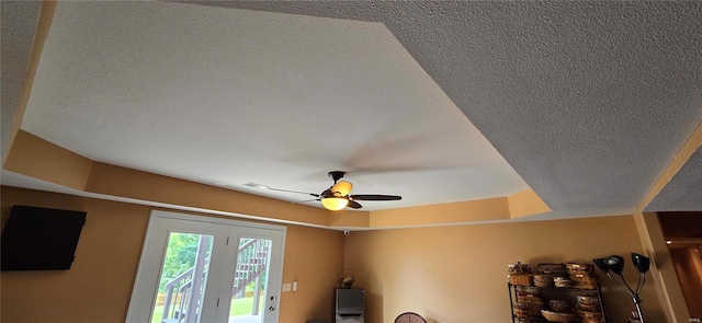 room details with a textured ceiling, ceiling fan, and a tray ceiling