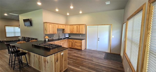 kitchen featuring dark hardwood / wood-style floors, black gas stovetop, light brown cabinets, and kitchen peninsula