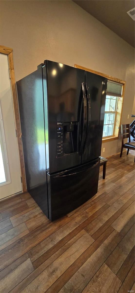 room details featuring hardwood / wood-style flooring and black refrigerator with ice dispenser