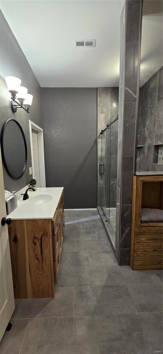 bathroom with a shower with door, vanity, and tile patterned flooring