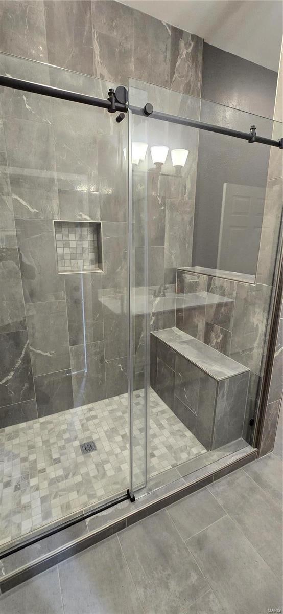 bathroom with a shower with shower door and tile patterned flooring