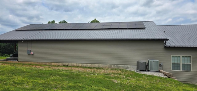 view of property exterior featuring solar panels, a yard, and central air condition unit