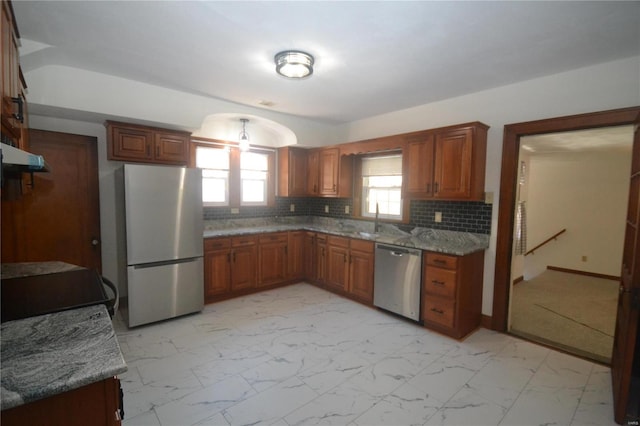 kitchen featuring sink, appliances with stainless steel finishes, tasteful backsplash, light stone counters, and extractor fan