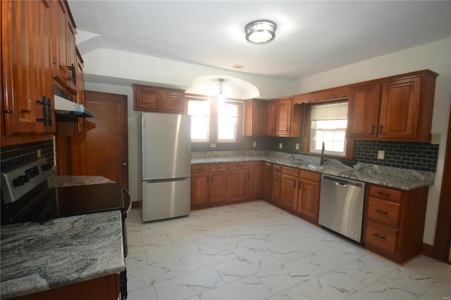 kitchen featuring stone counters, backsplash, stainless steel appliances, and sink