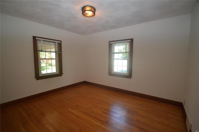 empty room with plenty of natural light and hardwood / wood-style floors