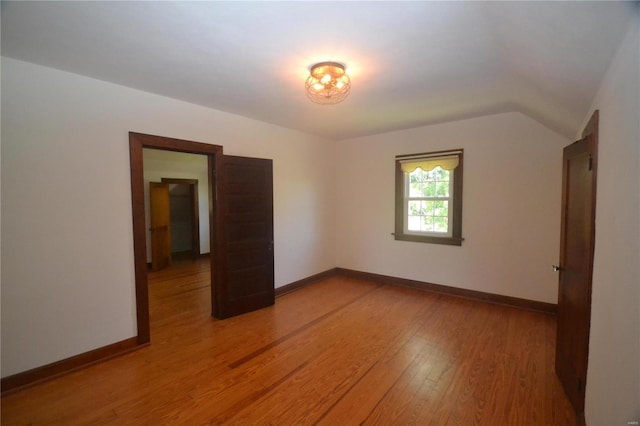 unfurnished room with hardwood / wood-style floors and lofted ceiling