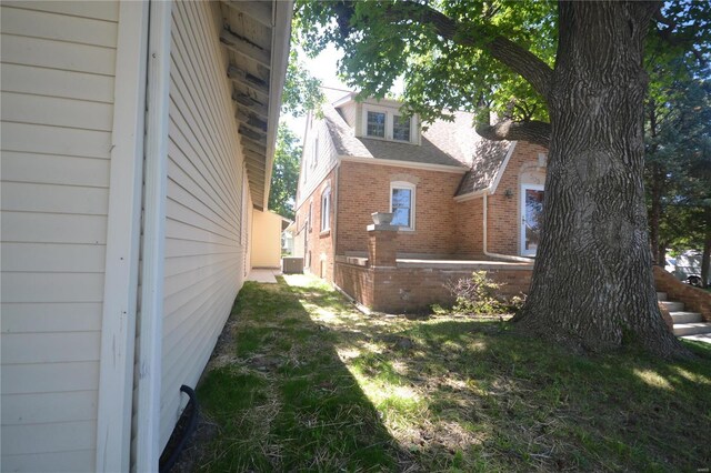 view of side of home with a lawn and cooling unit