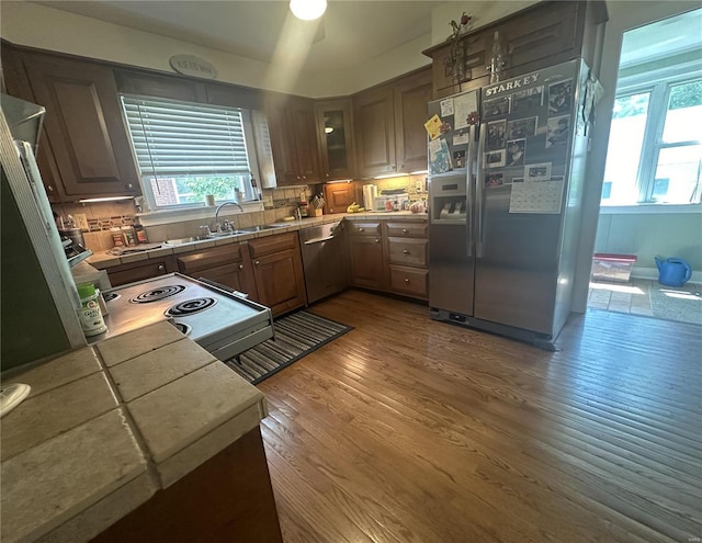 kitchen featuring sink, tile counters, stainless steel appliances, decorative backsplash, and hardwood / wood-style flooring