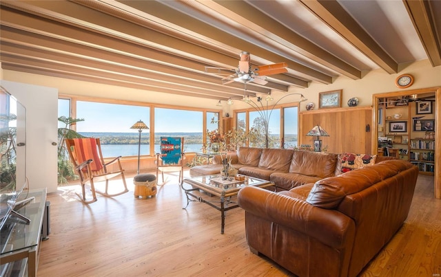 living room featuring beamed ceiling, plenty of natural light, light hardwood / wood-style floors, and a water view