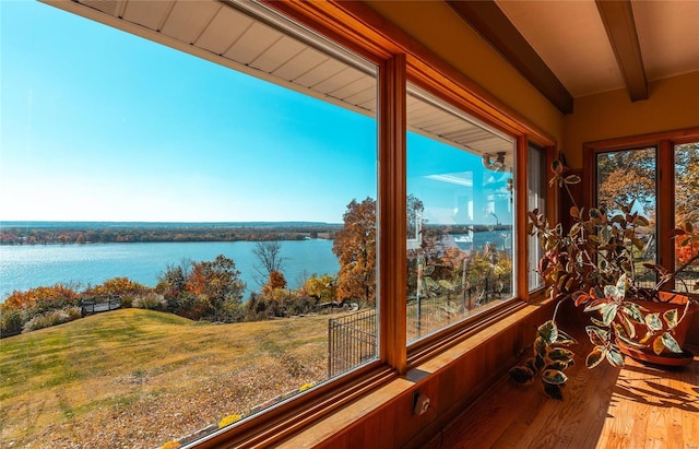 unfurnished sunroom featuring beamed ceiling and a water view