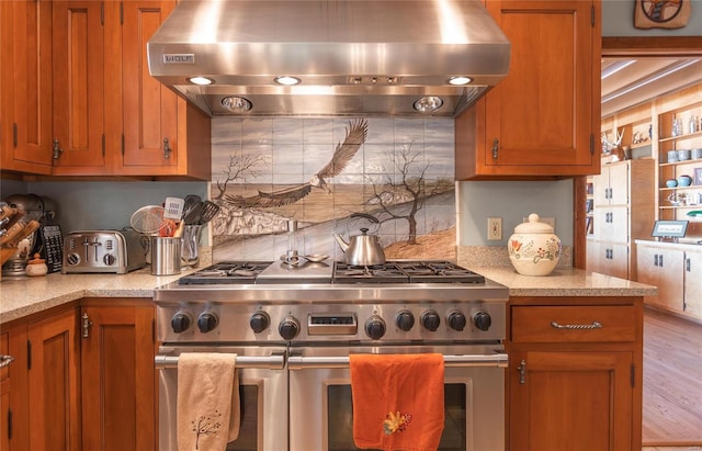 kitchen featuring tasteful backsplash, wall chimney exhaust hood, and range with two ovens