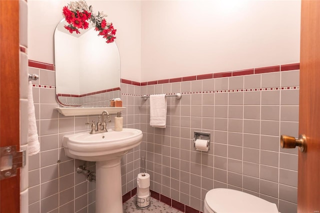 bathroom featuring tile patterned floors, toilet, and tile walls