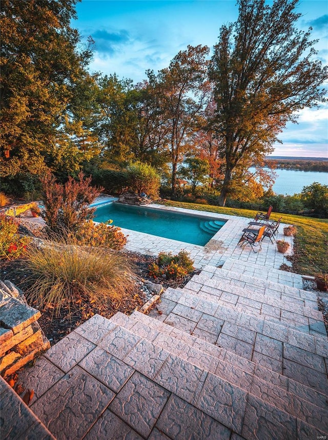 view of pool featuring a water view and a patio