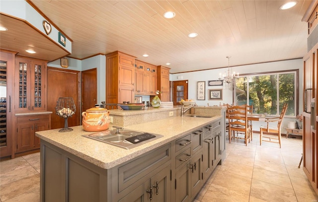 kitchen featuring wooden ceiling, a large island with sink, hanging light fixtures, sink, and light stone counters