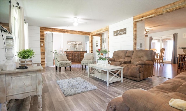 living room with ceiling fan, wooden walls, and hardwood / wood-style floors