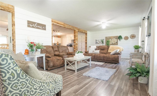 living room with ceiling fan, hardwood / wood-style floors, and wooden walls