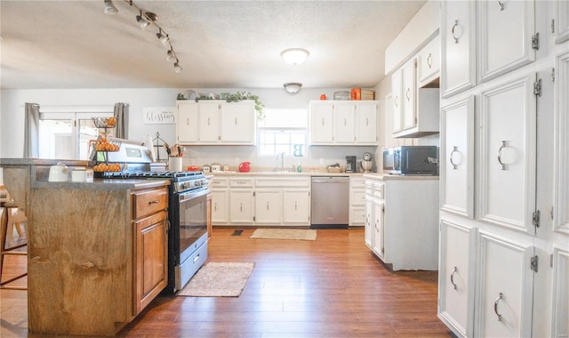 kitchen featuring dark wood-type flooring, a kitchen breakfast bar, white cabinets, and stainless steel appliances