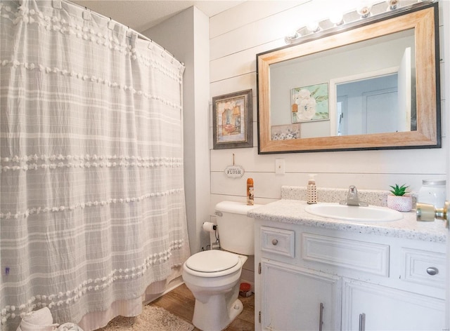 bathroom with vanity, toilet, wooden walls, and curtained shower