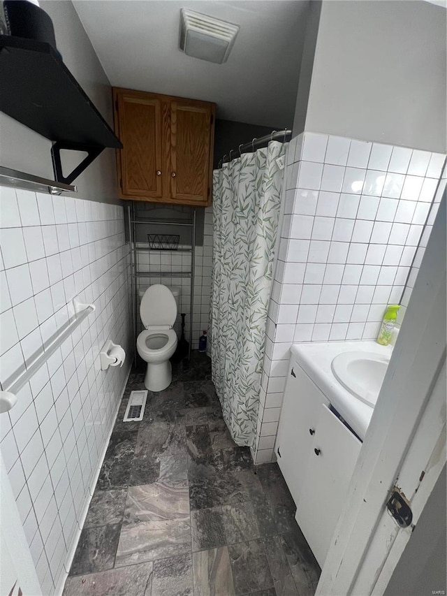 bathroom featuring vanity, toilet, and tile walls