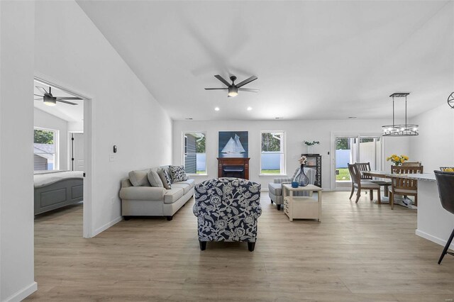 living room featuring ceiling fan with notable chandelier and light wood-type flooring