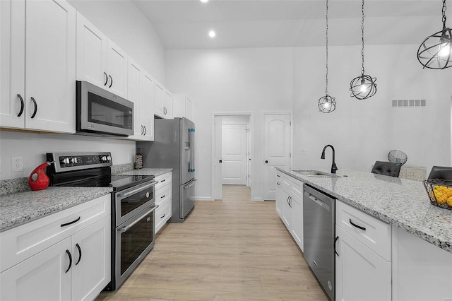 kitchen with sink, light stone counters, hanging light fixtures, stainless steel appliances, and white cabinets