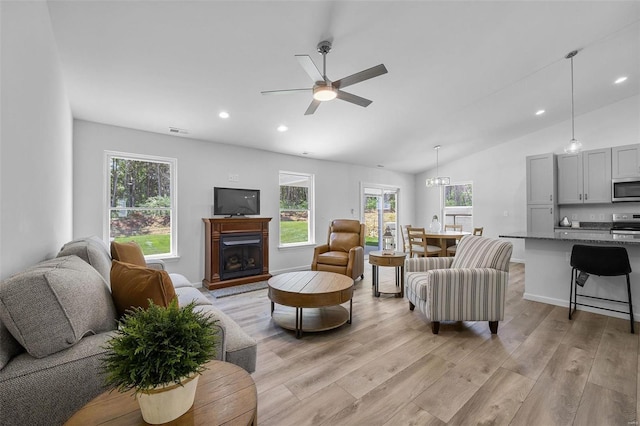 living room with ceiling fan, lofted ceiling, and light wood-type flooring