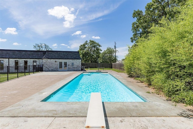 view of swimming pool with french doors, a diving board, and a patio area