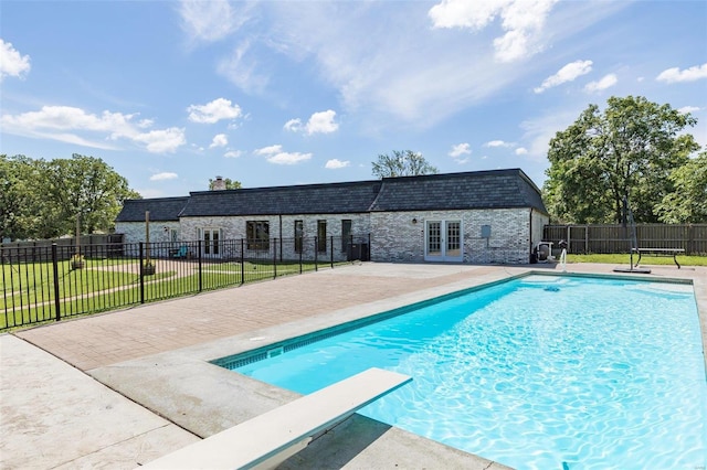 view of swimming pool featuring french doors, a yard, a diving board, and a patio