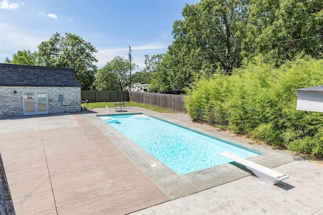 view of pool with a diving board and a patio area