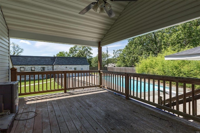 wooden terrace featuring a fenced in pool, ceiling fan, and a lawn