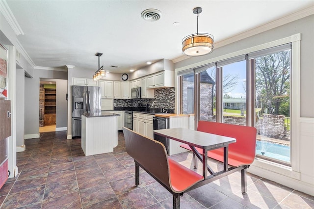 kitchen with pendant lighting, tasteful backsplash, a center island, black appliances, and crown molding