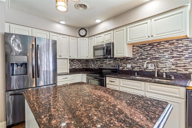 kitchen featuring white cabinetry, sink, dark stone counters, and appliances with stainless steel finishes