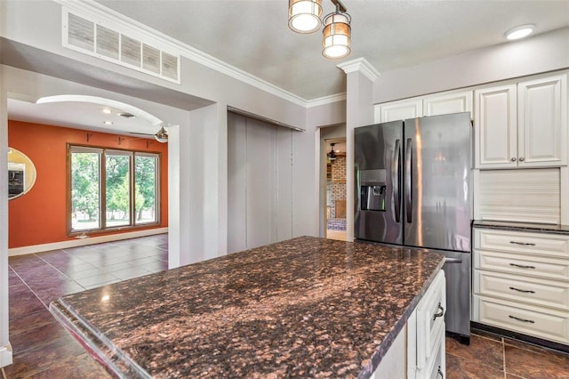 kitchen featuring white cabinetry, ornamental molding, stainless steel fridge, and dark stone countertops