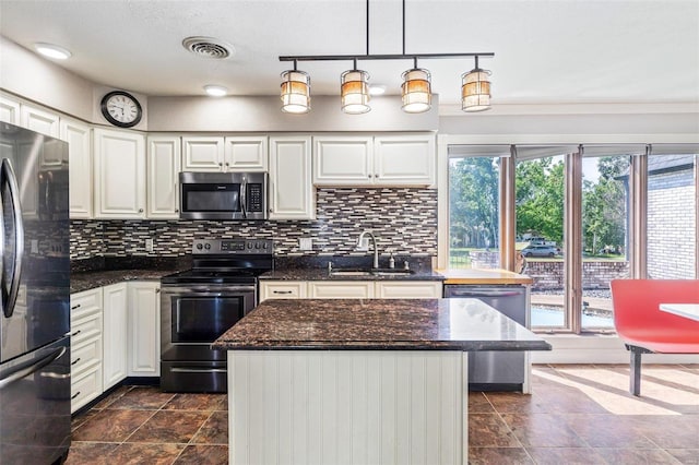 kitchen featuring sink, stainless steel appliances, a center island, white cabinets, and decorative light fixtures