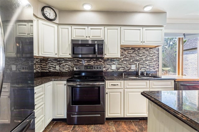 kitchen with sink, appliances with stainless steel finishes, white cabinetry, tasteful backsplash, and dark stone counters