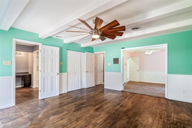 unfurnished bedroom featuring dark wood-type flooring, ceiling fan, beam ceiling, and a closet