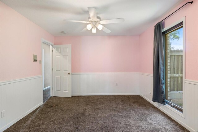 spare room with dark colored carpet and ceiling fan