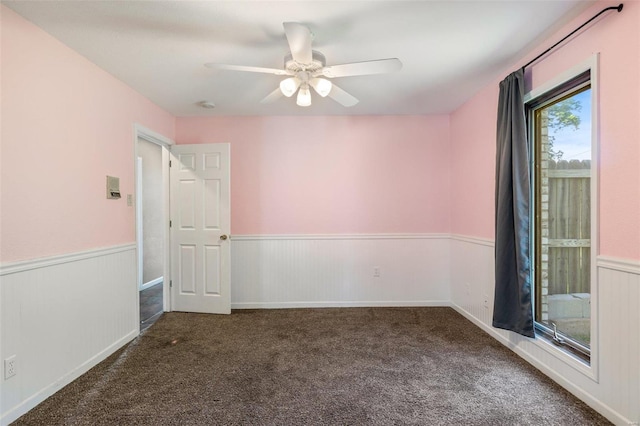 unfurnished room with ceiling fan and dark colored carpet