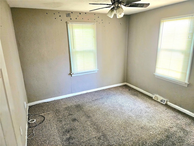 carpeted spare room with a wealth of natural light, visible vents, and baseboards