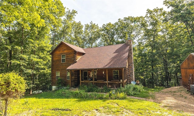 rear view of house featuring covered porch and a lawn