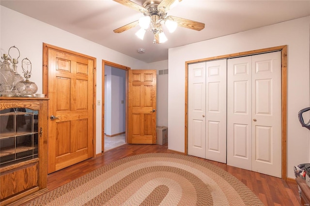 bedroom with dark wood-type flooring, ceiling fan, and a closet