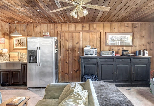 kitchen with appliances with stainless steel finishes, wood ceiling, sink, hanging light fixtures, and wood walls