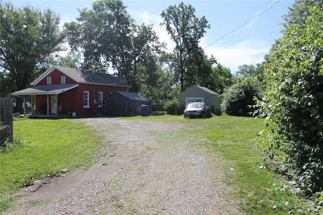 exterior space with a lawn, a garage, an outbuilding, and a porch