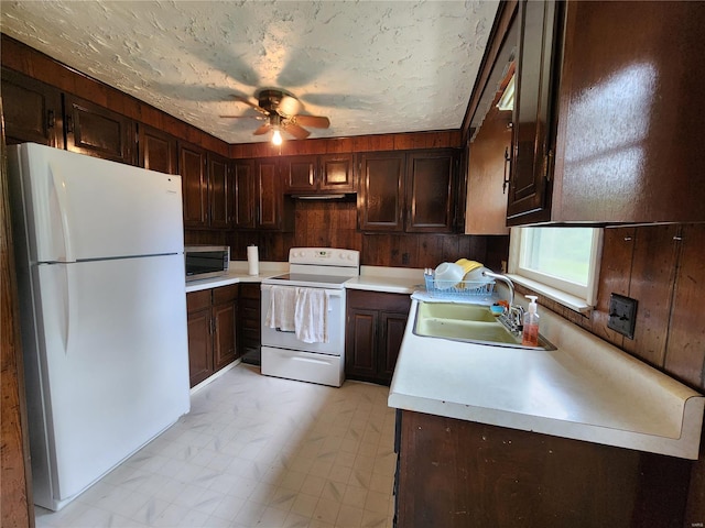 kitchen with dark brown cabinetry, light tile flooring, ceiling fan, sink, and white appliances