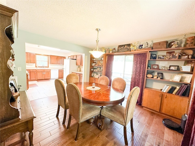 dining space featuring a textured ceiling, light hardwood / wood-style flooring, and sink