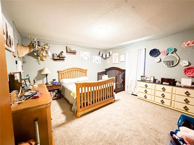 bedroom with carpet flooring, a crib, and a textured ceiling