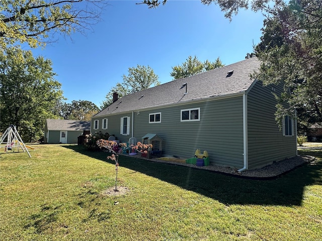 rear view of property featuring a playground and a yard