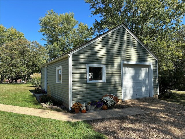 view of side of property with a garage, an outdoor structure, and a lawn