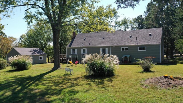 back of property featuring a yard and an outdoor structure