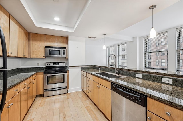 kitchen featuring dark stone countertops, sink, decorative light fixtures, and appliances with stainless steel finishes